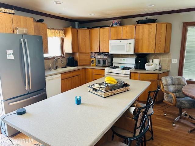 16754 Sarno Dr, Macomb, MI 48044 - kitchen with white appliances, light countertops, crown molding, a kitchen bar, and backsplash