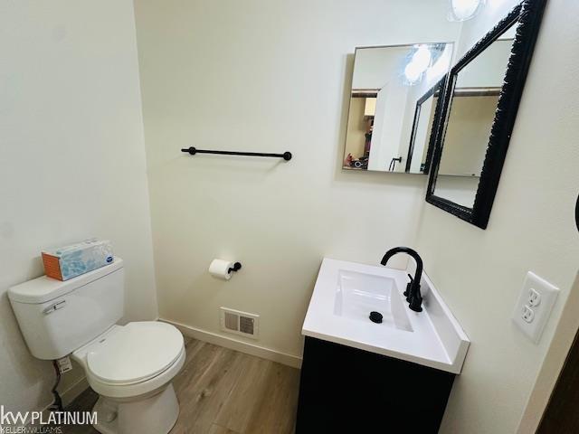 16754 Sarno Dr, Macomb, MI 48044 - bathroom with toilet, vanity, wood finished floors, and baseboards