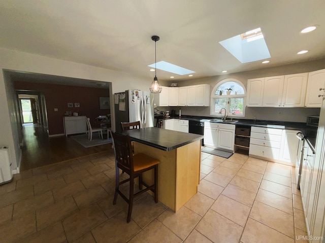 801 S Hemlock St, Iron Mountain, MI 49801 - kitchen with freestanding refrigerator, a skylight, dark countertops, white cabinetry, and recessed lighting