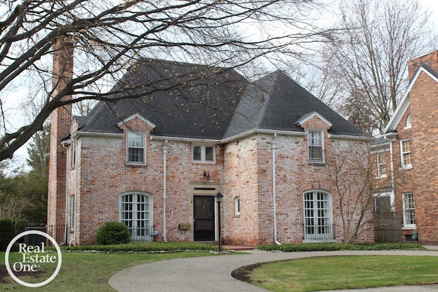 93 Moran Rd, Grosse Pointe Farms, MI 48236 - view of front of house with roof with shingles, a front lawn, and brick siding
