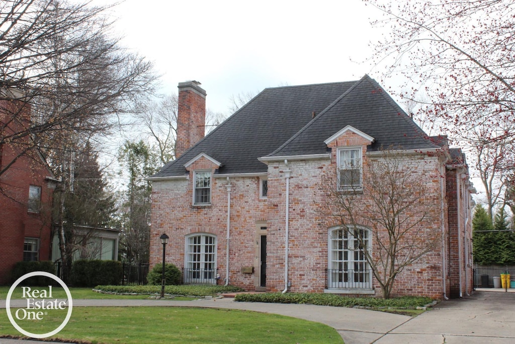 93 Moran Rd, Grosse Pointe Farms, MI 48236 - french country home featuring a chimney, brick siding, and a front lawn