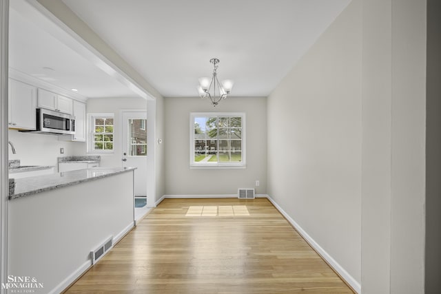 22920 Marter Rd, Saint Clair Shores, MI 48080 - unfurnished dining area with light wood-style floors, a chandelier, and baseboards