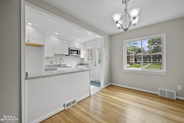 22920 Marter Rd, Saint Clair Shores, MI 48080 - kitchen featuring stainless steel microwave, a chandelier, white cabinets, light wood finished floors, and light stone counters