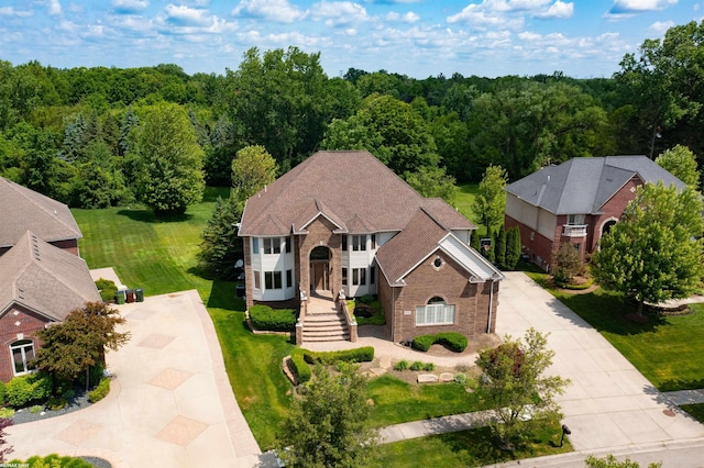 55733 Whitney Ct, Shelby Twp, MI 48315 - view of front facade with concrete driveway, brick siding, a view of trees, and a front lawn