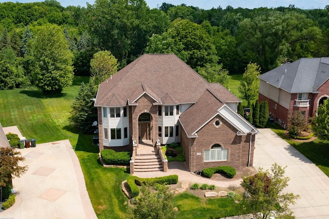 55733 Whitney Ct, Shelby Twp, MI 48315 - colonial-style house featuring brick siding, concrete driveway, and a wooded view
