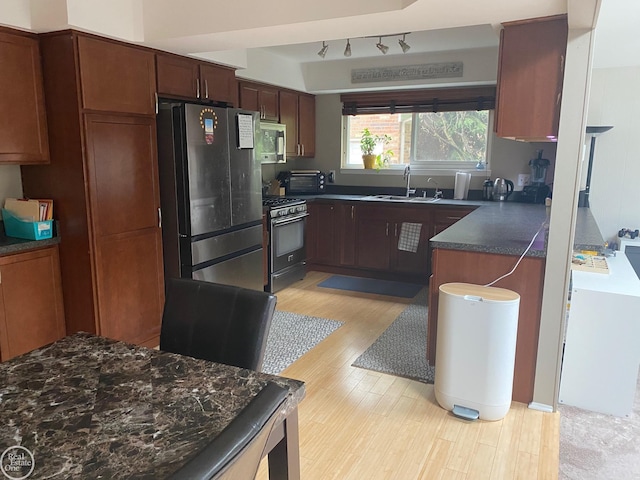 44854 Forest Trail Dr, Canton, MI 48187 - kitchen with stainless steel appliances, dark countertops, a sink, light wood-style flooring, and rail lighting