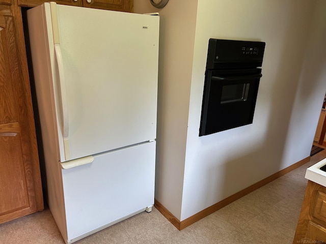 4590 Main St, Applegate, MI 48401 - kitchen featuring freestanding refrigerator, oven, baseboards, light floors, and brown cabinetry