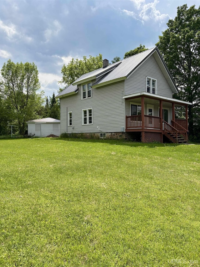 909 Sutherland Ave, Ironwood, MI 49938 - back of property with a chimney, a yard, covered porch, and metal roof