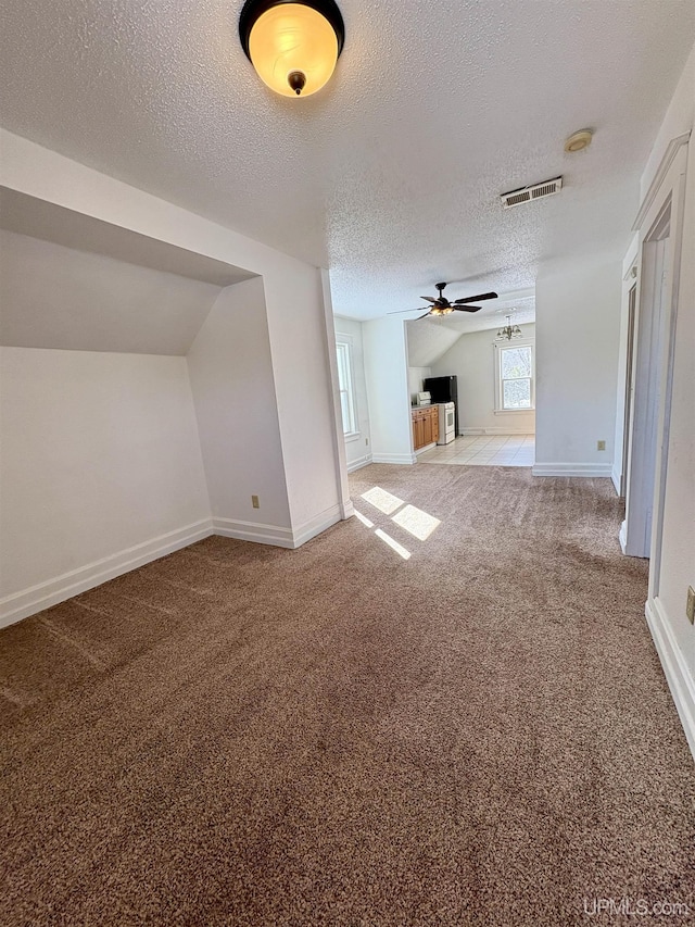 909 Sutherland Ave, Ironwood, MI 49938 - unfurnished living room featuring a textured ceiling, carpet, a ceiling fan, baseboards, and lofted ceiling