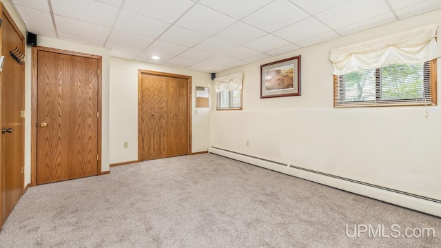 2119 S 21st Ave, Escanaba, MI 49829 - unfurnished bedroom featuring a baseboard heating unit, a drop ceiling, carpet floors, and a closet