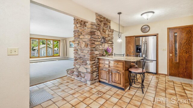 2119 S 21st Ave, Escanaba, MI 49829 - kitchen with stainless steel fridge, a peninsula, a kitchen bar, hanging light fixtures, and brown cabinets