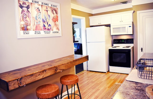 110 W Francis St, Ironwood, MI 49938 - kitchen with white appliances, light wood-style floors, white cabinetry, and a kitchen bar