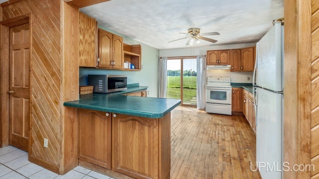 8102 W.5 Rd, Rapid River, MI 49878 - kitchen with white appliances, a peninsula, a ceiling fan, under cabinet range hood, and brown cabinets
