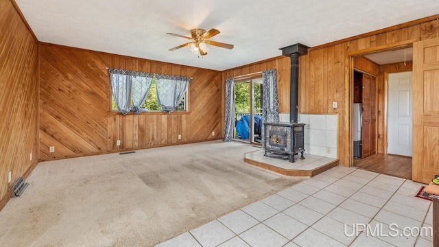 8102 W.5 Rd, Rapid River, MI 49878 - unfurnished living room with wood walls, a wood stove, ceiling fan, and baseboards