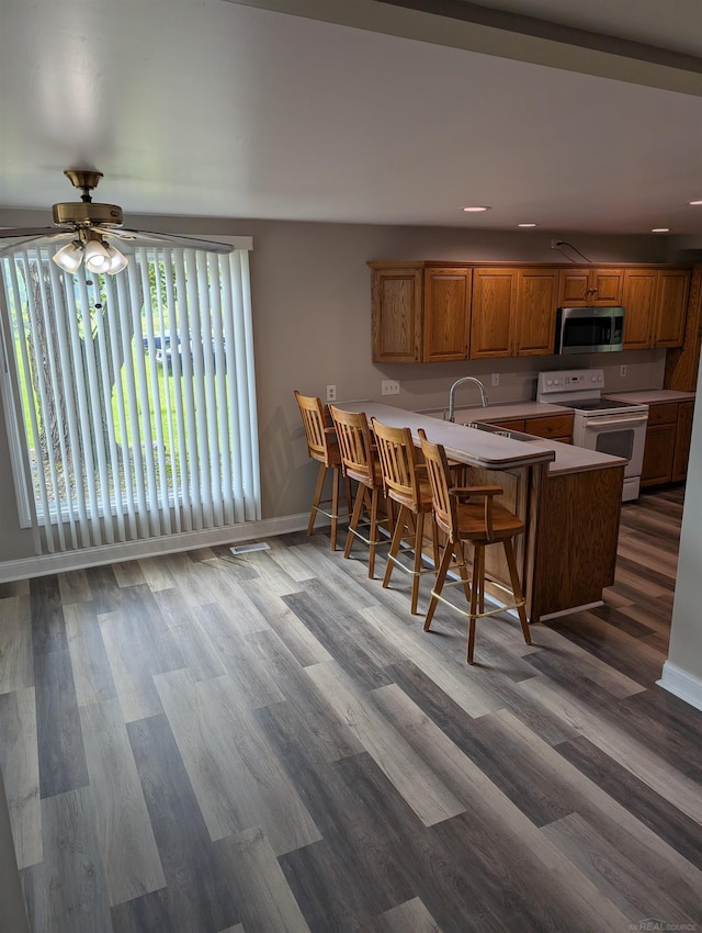 60606 Avendt Dr, New Haven, MI 48048 - kitchen featuring electric stove, stainless steel microwave, a peninsula, baseboards, and light countertops
