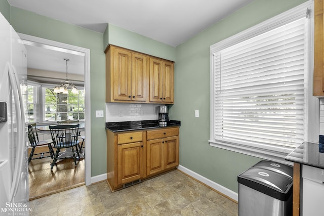 1984 Lancaster St, Grosse Pointe Woods, MI 48236 - kitchen with white refrigerator with ice dispenser, a chandelier, baseboards, and tasteful backsplash