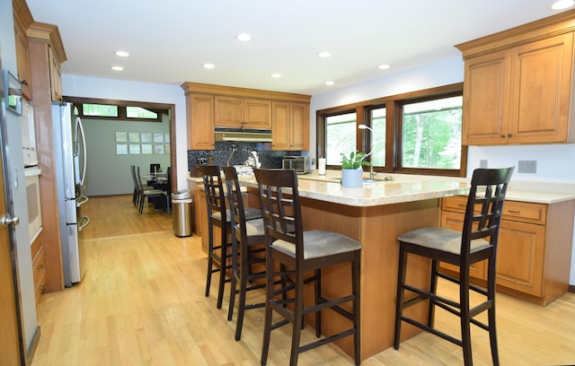 5400 Siebert St, Midland, MI 48640 - kitchen featuring freestanding refrigerator, light wood-style floors, under cabinet range hood, a kitchen breakfast bar, and recessed lighting