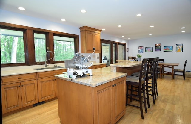 5400 Siebert St, Midland, MI 48640 - kitchen with a sink, a kitchen island, light wood-style flooring, brown cabinetry, and a kitchen bar