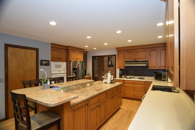 5400 Siebert St, Midland, MI 48640 - kitchen featuring white appliances, under cabinet range hood, a spacious island, a kitchen bar, and recessed lighting