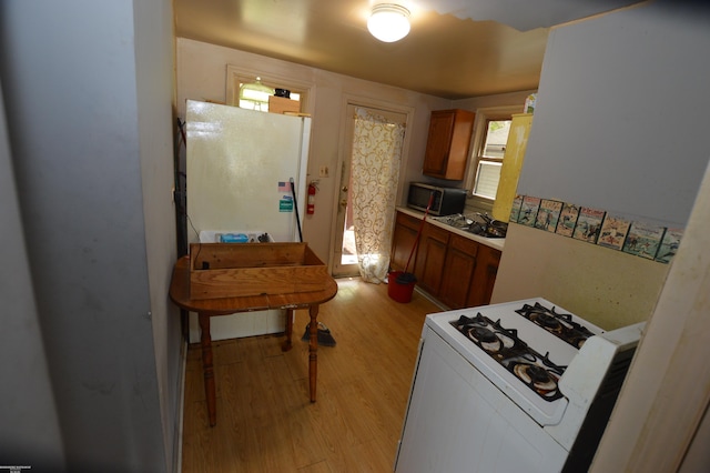17530 Oakdale St, Roseville, MI 48066 - kitchen with stove, light wood-style floors, brown cabinetry, and healthy amount of natural light