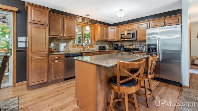 533 25th St, Gladstone, MI 49837 - kitchen featuring stainless steel appliances, light wood-style flooring, backsplash, and a breakfast bar