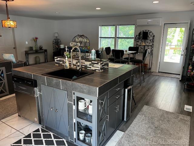 1335 28th St, Manistee, MI 49660 - kitchen featuring plenty of natural light, a wall mounted air conditioner, recessed lighting, stainless steel dishwasher, and tile countertops