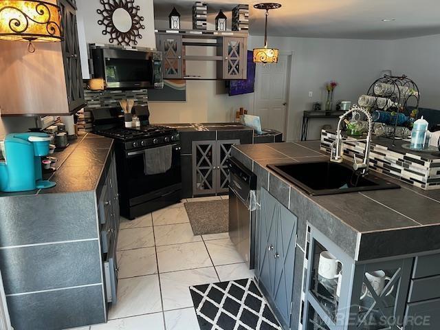 1335 28th St, Manistee, MI 49660 - kitchen featuring gas stove, dishwashing machine, tile counters, and decorative light fixtures