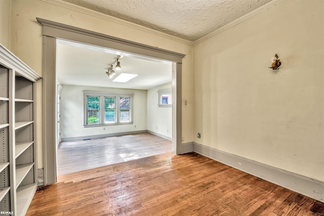 1200 Wells St, Ann Arbor, MI 48104 - spare room with wood finished floors, a skylight, track lighting, a textured ceiling, and ornamental molding