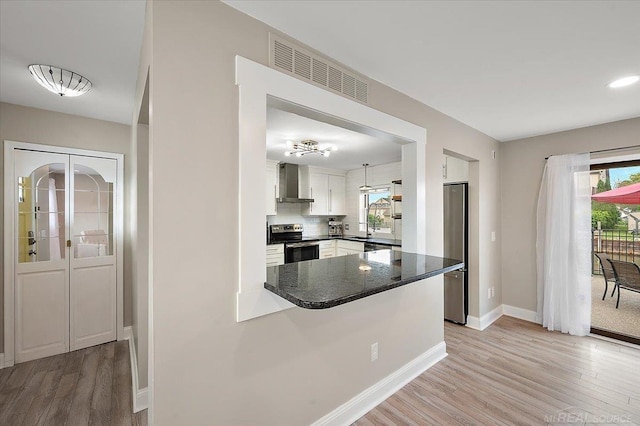 37738 Maplehill St, Harrison Twp, MI 48045 - kitchen with stainless steel appliances, wall chimney exhaust hood, light wood finished floors, dark countertops, and healthy amount of natural light