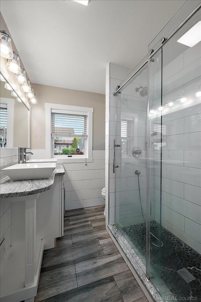 37738 Maplehill St, Harrison Twp, MI 48045 - full bathroom with vanity, a shower stall, a wainscoted wall, tile walls, and wood finished floors