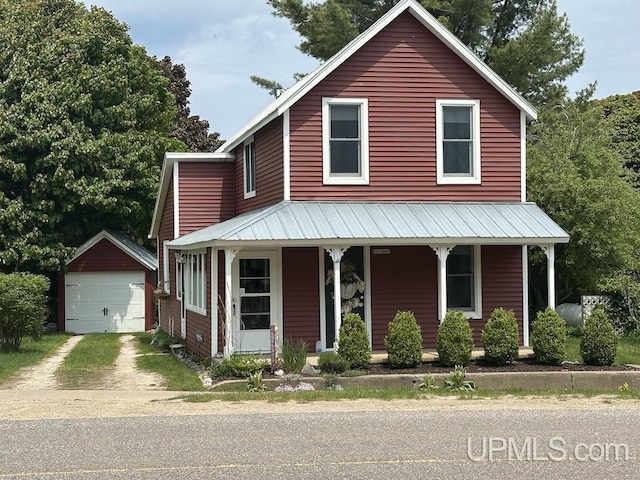 21988 E Everett Ave, Grand Marais, MI 49839 - view of front facade with covered porch, an outbuilding, a detached garage, and dirt driveway