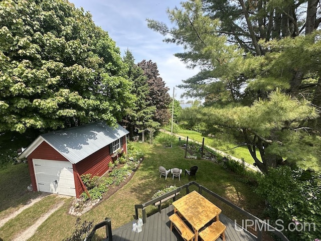 21988 E Everett Ave, Grand Marais, MI 49839 - view of grassy yard with an outbuilding, dirt driveway, a wooden deck, a detached garage, and view of scattered trees