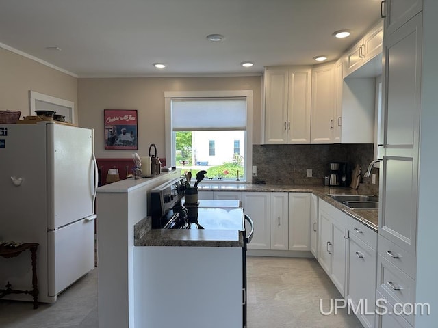 21988 E Everett Ave, Grand Marais, MI 49839 - kitchen featuring freestanding refrigerator, ornamental molding, decorative backsplash, white cabinets, and a center island