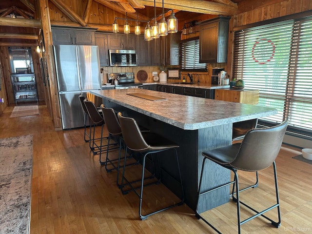 5847 County 513 T Rd, Rapid River, MI 49878 - kitchen featuring stainless steel appliances, light wood-type flooring, a kitchen bar, a center island, and decorative light fixtures