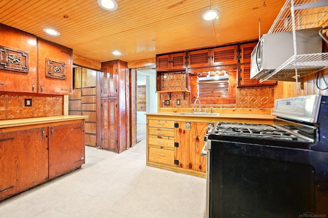 9970 Sedlock Ave, White Lake, MI 48386 - kitchen featuring gas range, white microwave, wooden walls, light countertops, and light flooring