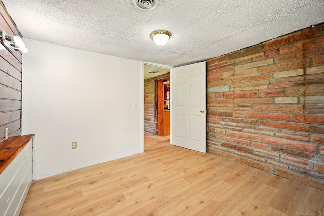 9970 Sedlock Ave, White Lake, MI 48386 - empty room featuring light wood-type flooring, brick wall, and a textured ceiling