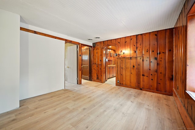 9970 Sedlock Ave, White Lake, MI 48386 - spare room featuring wooden walls, light wood-style flooring, and arched walkways