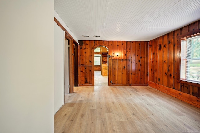 9970 Sedlock Ave, White Lake, MI 48386 - spare room featuring arched walkways, wooden walls, and light wood-style flooring