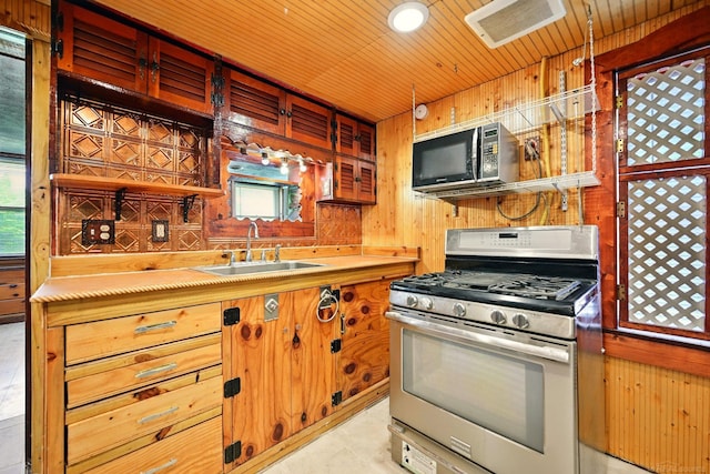 9970 Sedlock Ave, White Lake, MI 48386 - kitchen featuring stainless steel range with gas stovetop, black microwave, open shelves, wooden walls, and light countertops