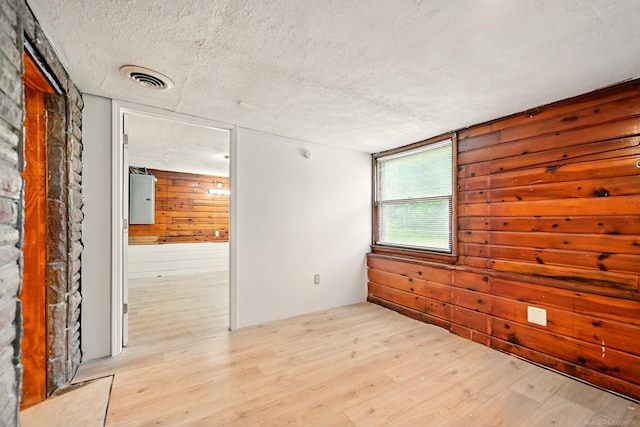 9970 Sedlock Ave, White Lake, MI 48386 - unfurnished room with a textured ceiling, wood walls, light wood finished floors, and electric panel
