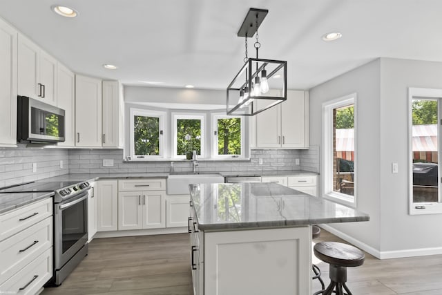 6767 Puttygut Rd, East China, MI 48054 - kitchen featuring stainless steel appliances, recessed lighting, light stone countertops, backsplash, and a kitchen breakfast bar