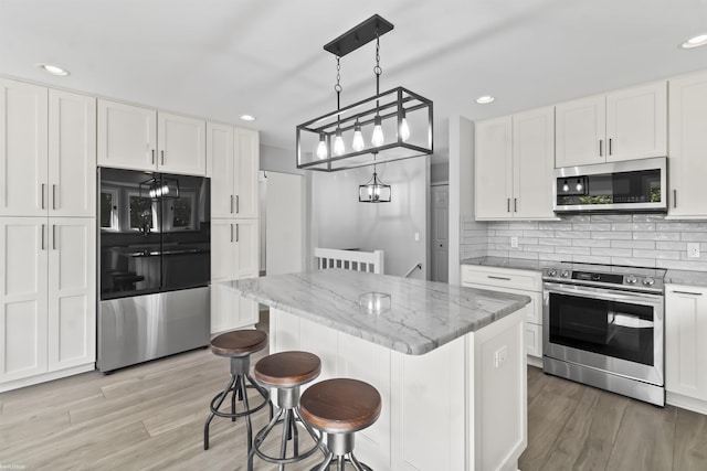 6767 Puttygut Rd, East China, MI 48054 - kitchen with appliances with stainless steel finishes, white cabinetry, light wood-style floors, backsplash, and recessed lighting