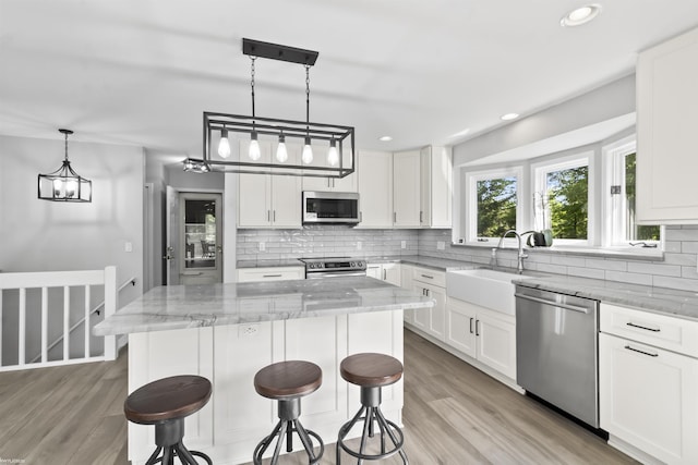 6767 Puttygut Rd, East China, MI 48054 - kitchen with stainless steel appliances, a center island, light stone countertops, tasteful backsplash, and a breakfast bar