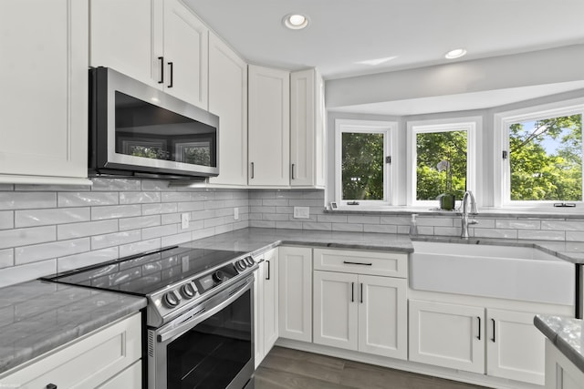 6767 Puttygut Rd, East China, MI 48054 - kitchen with appliances with stainless steel finishes, light stone counters, white cabinets, backsplash, and recessed lighting