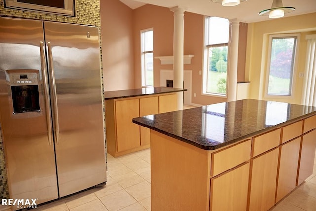 21832 Preserve Ct, Macomb Twp, MI 48042 - kitchen featuring stainless steel fridge, light tile patterned floors, decorative columns, light brown cabinets, and dark stone counters