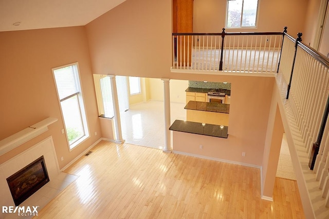 21832 Preserve Ct, Macomb Twp, MI 48042 - unfurnished living room with healthy amount of natural light, wood finished floors, ornate columns, a tiled fireplace, and a towering ceiling