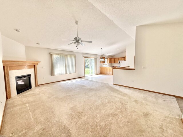 1248 S Hemlock Rd, Hemlock, MI 48626 - unfurnished living room with a textured ceiling, light colored carpet, a ceiling fan, vaulted ceiling, and a tile fireplace