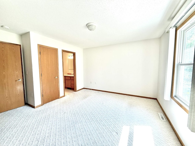 1248 S Hemlock Rd, Hemlock, MI 48626 - unfurnished bedroom with light carpet, a textured ceiling, and ensuite bathroom