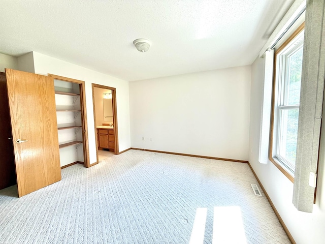 1248 S Hemlock Rd, Hemlock, MI 48626 - unfurnished bedroom featuring light carpet, a textured ceiling, and ensuite bathroom