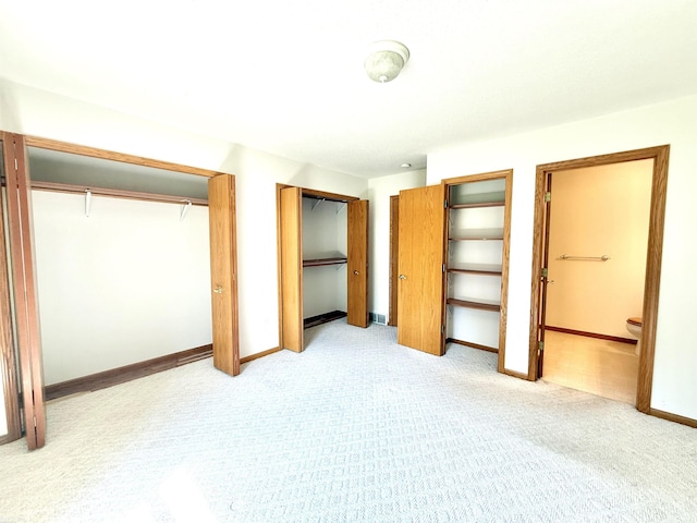 1248 S Hemlock Rd, Hemlock, MI 48626 - unfurnished bedroom featuring light colored carpet, ensuite bathroom, and two closets